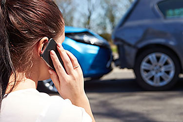 woman on phone in front of two cars in accident