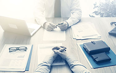 photo of two people at a desk with papers and laptop, having a discussion. wrongful death lawsuit