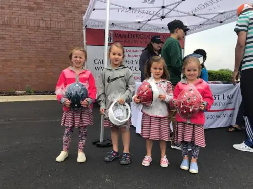 Four girls standing in front of VanDerGinst Law tent with new helmets