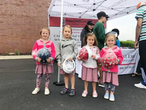 Four girls standing in front of VanDerGinst Law tent with new helmets