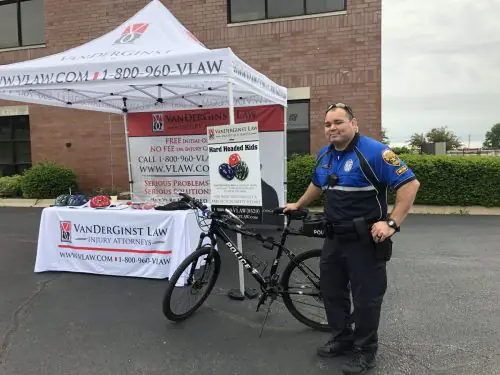 Police officer standing next to bike in front of VanDerGinst Law tent