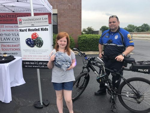 photo of police officer on a bike with girl holding helmet beside them