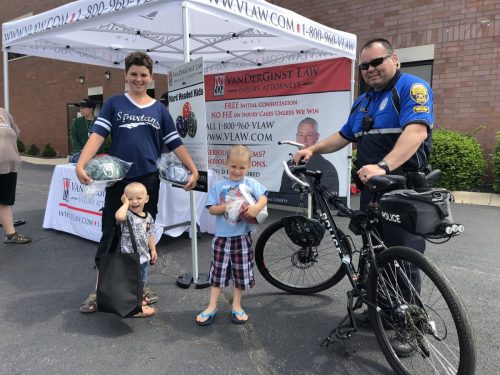 Police officer next to his bike with three children with helmets standing next to him
